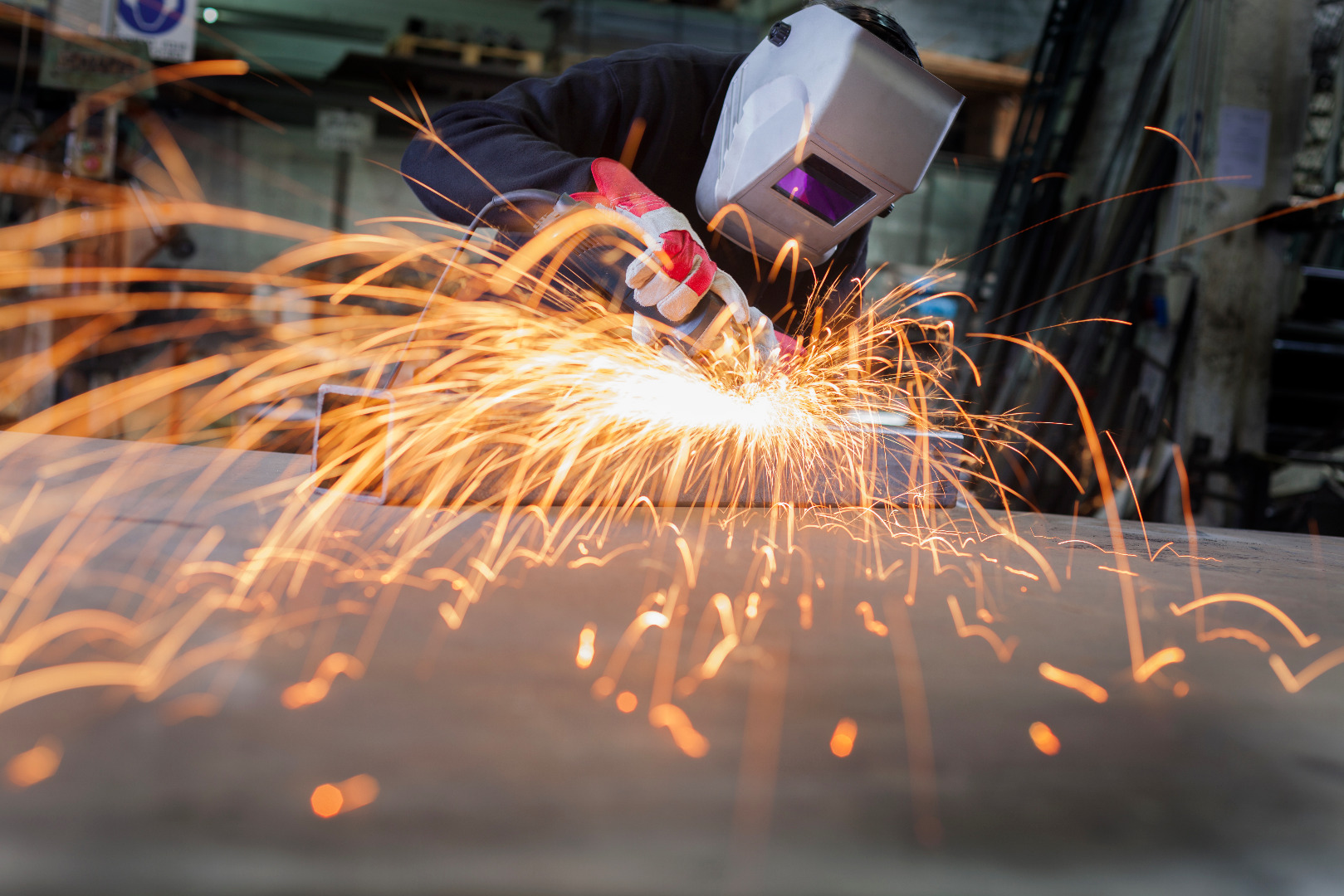 Metal wroker in a factory grinding with sparks